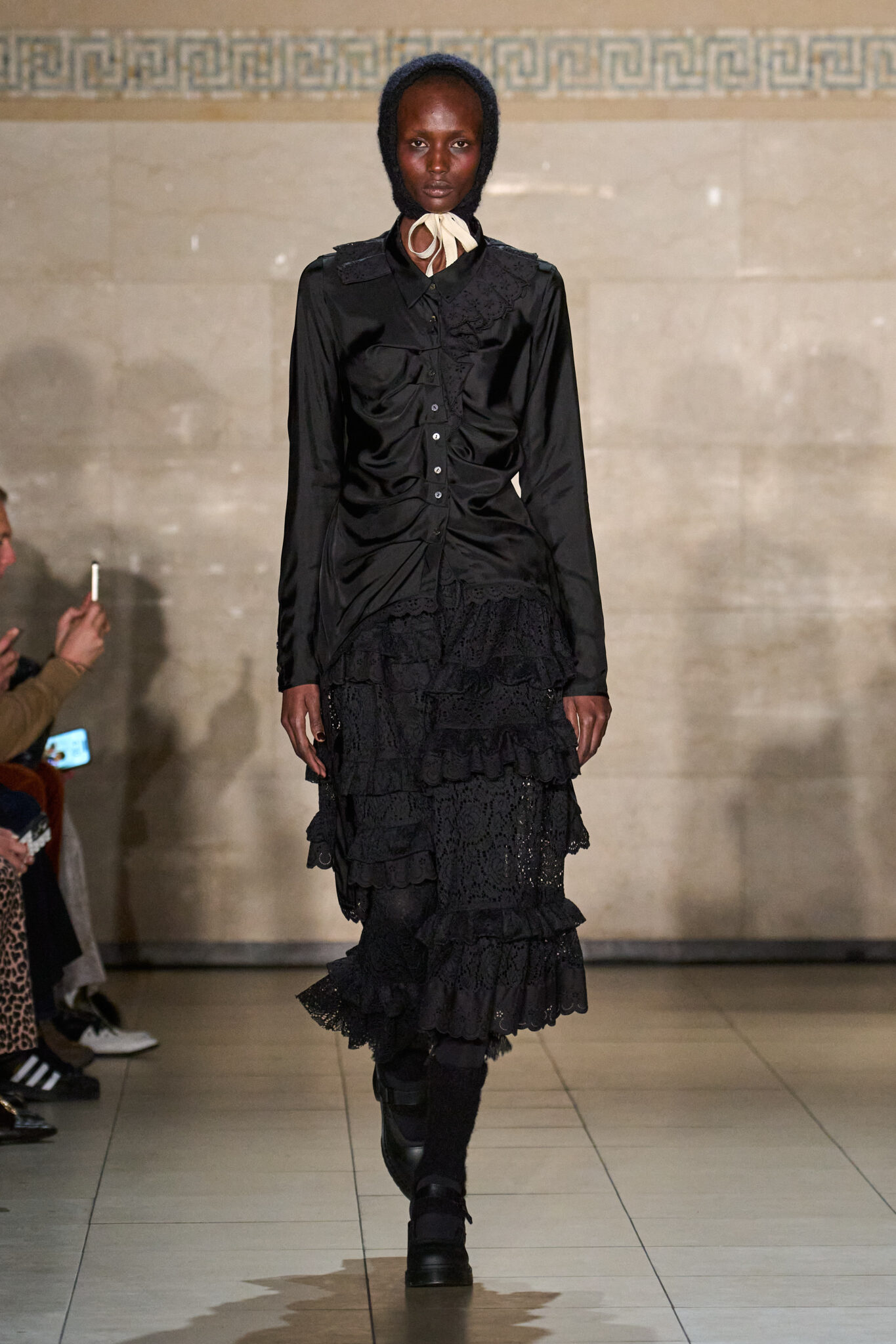 Runway look: black fitted jacket with a ruffled black skirt, Meruert Tolegen Fall/Winter 2025